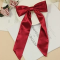 Elegant wine red satin bow hair clip with long ribbons on a white decorative plate - Red