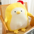 Cute yellow plush penguin toy wearing a red Christmas hat sitting on a wicker chair - Yellow