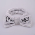 Detail shot of grey plush headband featuring OMG embroidered letters and soft bow texture - Gray