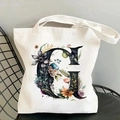 Detailed close-up of a white canvas tote bag with a floral letter G print on a chair - Letter G / 35*40cm