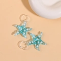 Detailed close-up of blue glass starfish pendants with white polka dots for jewelry DIY - Sky Blue