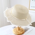 Detailed view of women's straw sun hat with wavy lace trim and elegant pearl accents - Beige