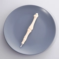 Unique bone-shaped ballpoint pen in cream white plastic on a blue ceramic plate - Style B (Phalange Shape)