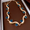 Dettaglio di una collana dorata a onde con pietre preziose blu in una scatola regalo - Collana - Oro - Blu