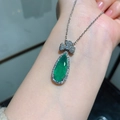 Green pear-cut Paraiba gemstone necklace set with silver bow design on model - Emerald Green Pendant