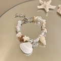 Dettaglio di bracciale con conchiglie, perle e stella marina su riflesso - Stile Stella Marina Conchiglia / Bianco