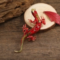 Vintage lizard brooch with vibrant red enamel and green crystals on a rustic wood base - Red Enamel with Red and Green Stones