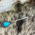 Detail van vintage turquoise haarclip met zilveren bloemengravures op een achtergrond van bont - Druppel Turkoois