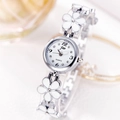 Primer plano de reloj de cuarzo plateado con flores de esmalte blanco y esfera redonda - Banda Plateada Esfera Blanca