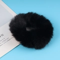Soft black plush faux fur scrunchie hair tie on a bright sky blue background - Black