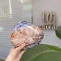 Macro detail of oval marble texture clutch with glossy finish and metal clasp closure - Grey-brown