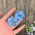 Macro detail of sky blue flower earrings with golden edges and beaded metal centers - Silver Needle / Blue