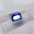 Detailopname van een zilveren titanium ring met een grote rechthoekige blauwe edelsteen - US Maat 5 / Blauw