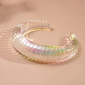 Macro view of wide iridescent acrylic cuff bracelet with textured ribbed surface and neon glow - Coarse Texture