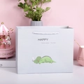 Hellgraue Papier-Geschenktüte mit grünem Dinosaurier-Motiv und weißen Kordelgriffen - Grüner Dinosaurier