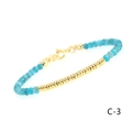 Detailed close-up of blue faceted gemstone beads and textured gold tube on the bracelet - Apatite Flat Bead