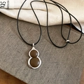 Close-up of a gourd-shaped pendant with dark brown beads and silver metal frame - Brown