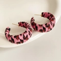 Detail of pink and black leopard print fabric wrapped hoop earrings on a white plate - Pink