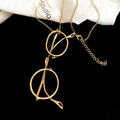Détail d'un collier avec pendentif en forme de lunettes dorées sur fond minimaliste noir et blanc - Doré