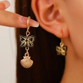 Dettaglio di orecchini a conchiglia con farfalla nera indossati da una modella - Stile Pendente Oro Nero Farfalla Conchiglia (Z-371) / oro kc
