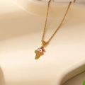 Macro shot of gold African map necklace with a Santa Claus hat on a ceramic tray - Santa Letter T