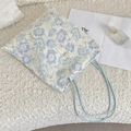 Nahaufnahme der hellblauen floralen Spitzenstickerei und des Textiletiketts der Tasche - Blau + Retro-Spitze