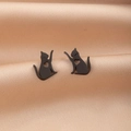 Primer plano de pendientes gato negro con recorte de corazón sobre seda beige - Negro