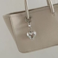 Lychee texture leather bag detail featuring a silver heart-shaped metallic charm - Buckle Heart Style