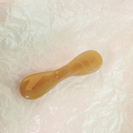 Κοντινή λήψη εργαλείου μασάζ προσώπου σε χρώμα κεχριμπάρι σε ροζ φόντο - Καραμέλα