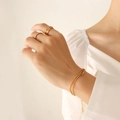 Zweilagiges goldenes Perlenarmband und minimalistische Ringe am Handgelenk der Frau - 14+5cm / Gold