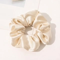 Macro shot of off-white silk scrunchie showing glossy satin texture and elegant folds - Champagne