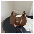 Detail of a brown crescent bag with a silver bow accent and adjustable shoulder strap - Dark Brown