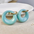 Close-up of light blue resin oval earrings with 18K gold plated hoops on a stone tray - Gold-Blue