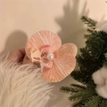 Elegant pink orchid hair clip with pearl detail held against a warm festive background - Orange Pink