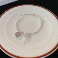 Nahaufnahme Silberperlenarmband mit rosa Zirkon-Herz und Perlen-Schleifen-Anhängern - Armband - Silber