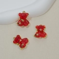 Three red gummy bear pendants in resin with gold trim and star accents on beige background - Red