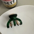 Vue détaillée d'une pince à cheveux vert foncé à motif écaille de tortue et accent doré - Vert