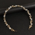 Macro detail of bridal headband with golden leaves and sparkling rhinestone flowers - Gold