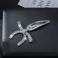 Elegante pinza de pelo de metal plateado con lazo y diamantes sobre cuero negro - Lazo