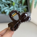 Detail of a dark brown bow-shaped hair claw clip with glossy finish and gold spring - Chocolate - Small Bowknot