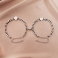 Close-up of magnetic heart and round pendants on silver cuban link bracelets for couples - Pair of Cuban Chain Heart and Round