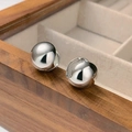 Minimalistische zilveren bolvormige oorringen gepresenteerd op een houten juwelendoos - Koper / Witgoud