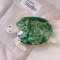 Detailed top view of green acetate sea turtle hair claw clip on a neutral fabric background - Large / Green