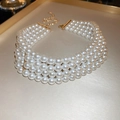 Dettaglio di una collana di perle a quattro strati con chiusura dorata su vassoio - Collana-Bianco