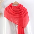 Detail of red crinkled linen scarf with frayed edges hanging on a white wooden hanger - Red
