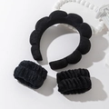 Close-up of black sponge cloud headband set with matching wristbands on a white decor base - Black Headband And Wristbands Set