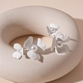 Detail von mattweißen Blumen-Ohrsteckern mit Perlenmitte auf minimalistischem Display - Weiße Perlen-Blumenohrstecker (Silberstift)