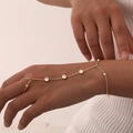 Detailed close-up of an 18K gold-plated hand chain with bezel-set round zircons on the wrist - Four Zirconia & Bead / Gold
