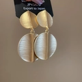 Dettaglio di orecchini a pendente tondi in oro opaco spazzolato con design a foglia - Oro