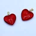 Close-up of two red glass heart-shaped pendants with metallic clasps on white background - Red